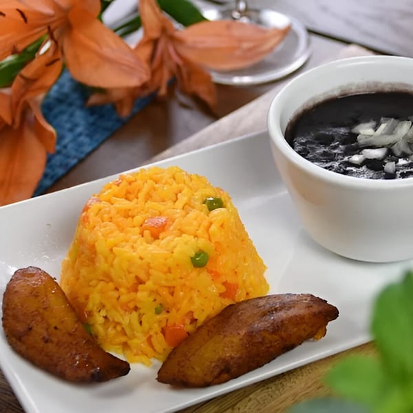 Cuban yellow rice with peas and carrots, fried plantains, and a side of black beans.