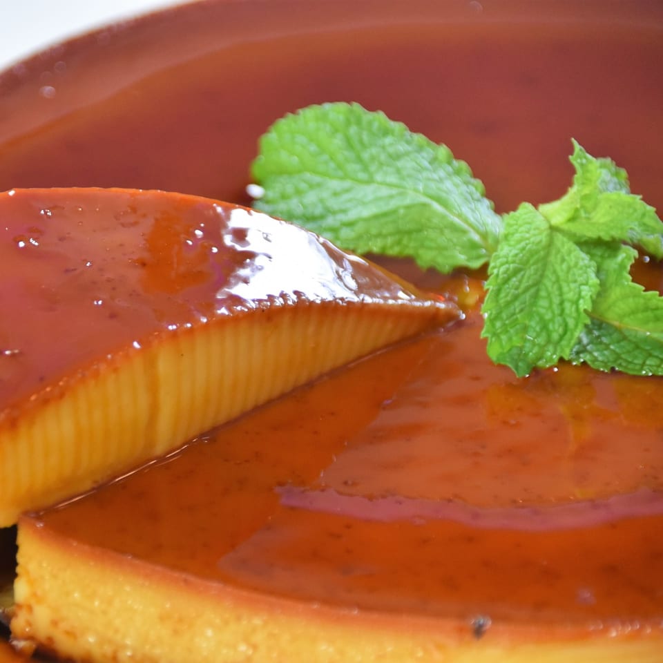 Close-up of a glazed pastry topped with fresh mint leaves on a terracotta plate.