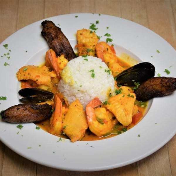 Cuban seafood dish with shrimp, mussels, fish, rice, and plantains in a rich sauce.